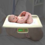 Alpha SRSB125 digital baby scale with a baby on the tray