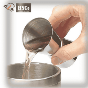 Pouring liquor from a steel peg measure into a mixing tin