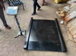 HSCo wheelchair scale with chequered platform, ramps and display on stand outside a hospital