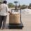 A worker steadies a jute bag of kapas on a chequered platform scale in a cotton yard