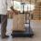 Worker holds an open jute sack of soybean on a chequered platform scale in a shed